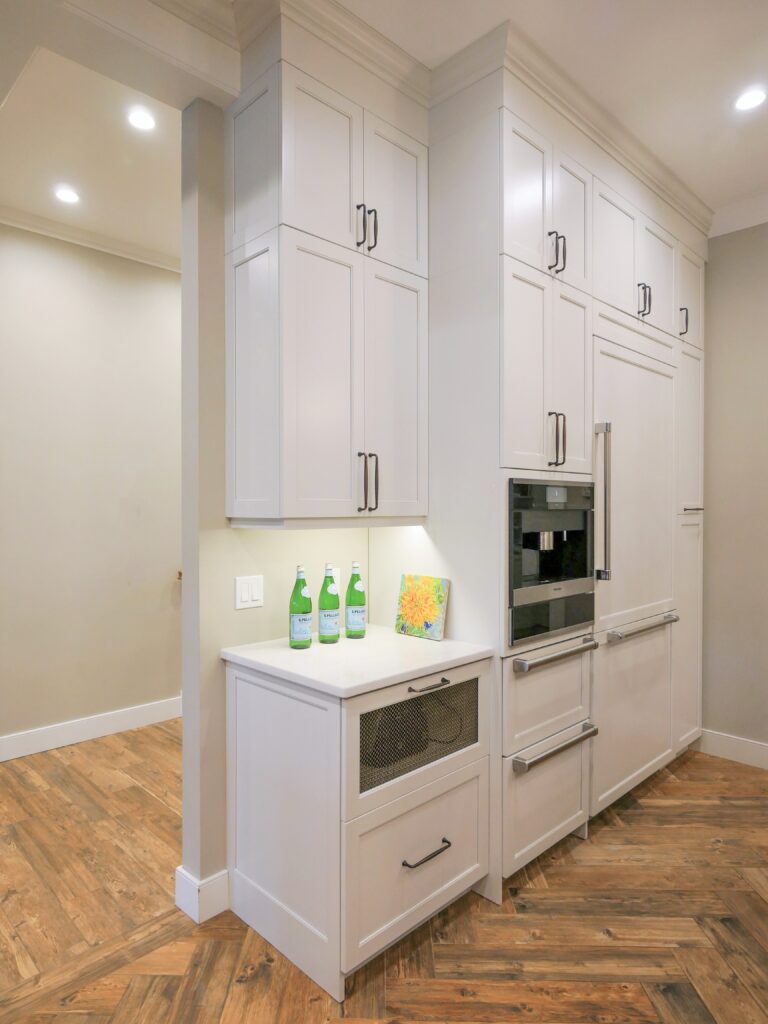 Traditional white kitchen with floor to ceiling pantry storage, miele built-in coffee machine, sub-zero built-in freezer drawers and pull-out pantry