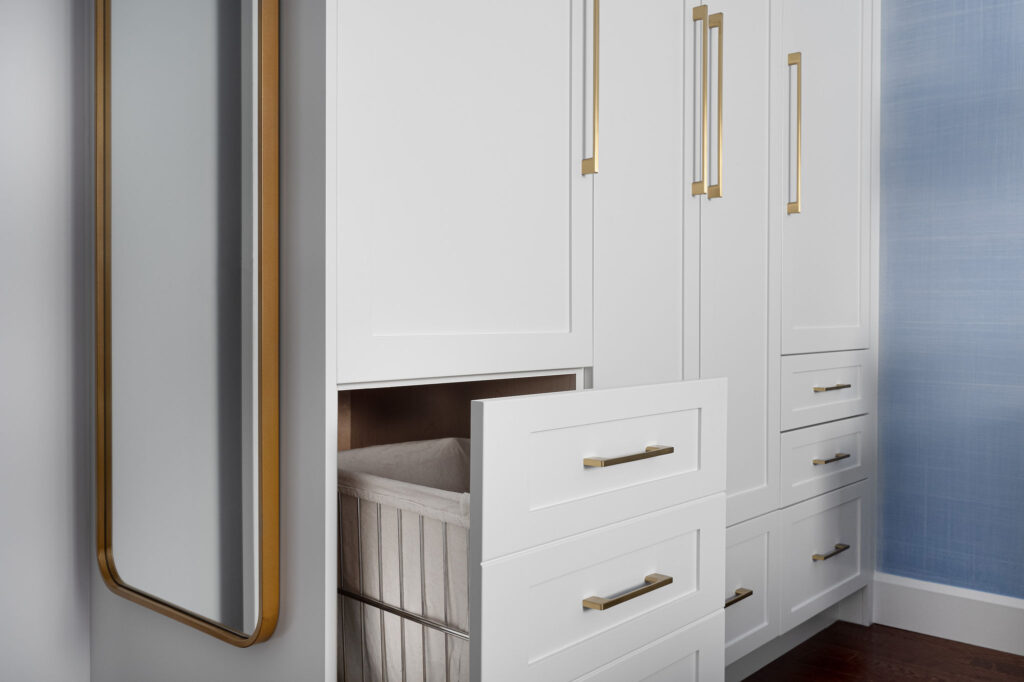 Built-in Closet cabinetry, white with gold hardware and pullout hamper