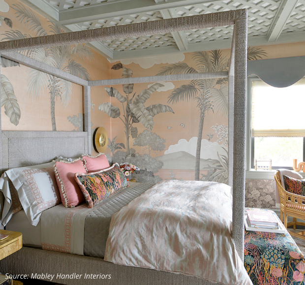 traditional coastal style bedroom in peach and gray.  Platform canopy bed in gray fabric, walls with palm tree wallpaper in gray and peach and trellis detail on ceiling 