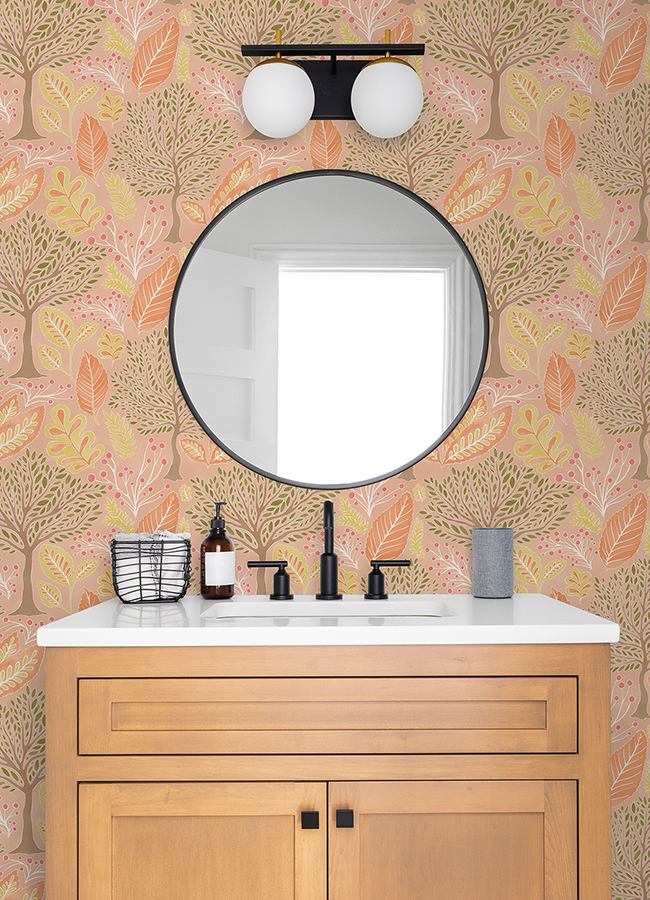 Powder room vanity in natural wood with bronze fixtures and peach toned patterned wallpaper