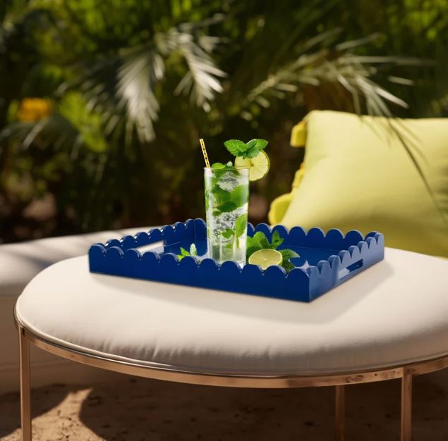 Blue lacquered tray with scalloped edges, on a round white ottoman with brushed gold frame.  custom accessories and furniture in Ottawa.